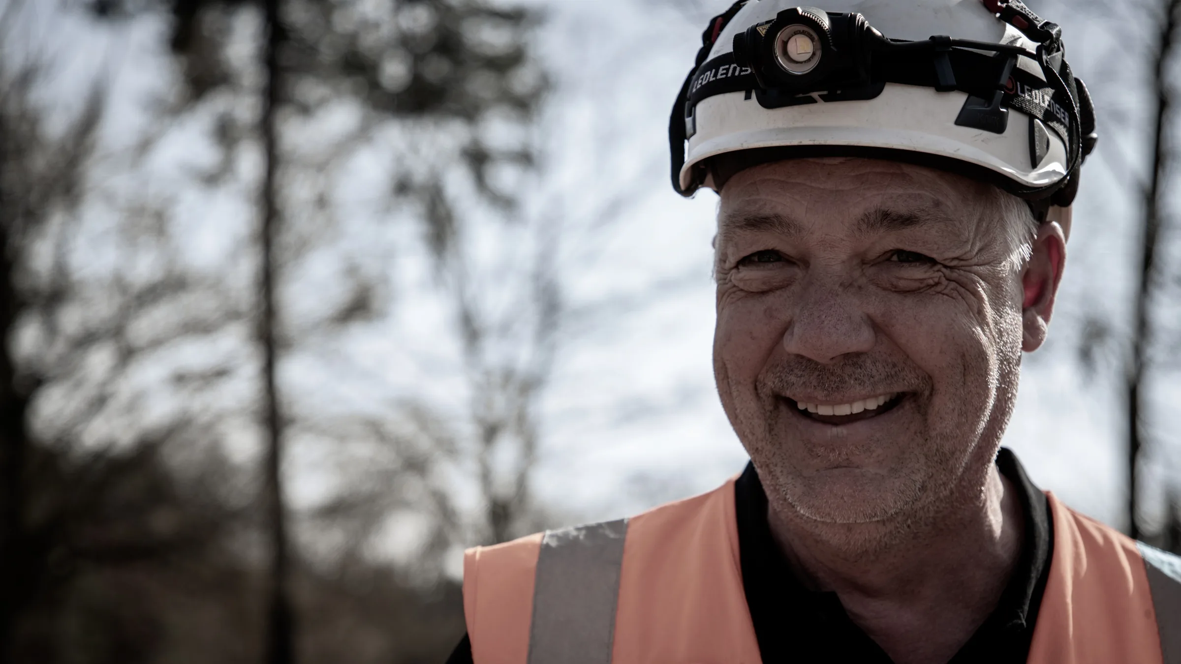 Dirk Orth laechelnd, Portrait mit Bauhelm und Stirnlampe